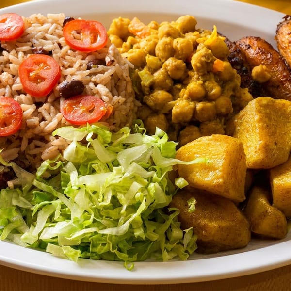 White plate with rice and beans, chickpeas, fried plantains, curried potatoes, and lettuce.