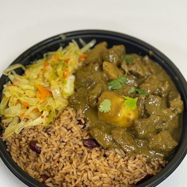 Green curry with meat and potatoes, rice and peas, and steamed cabbage in a black bowl.