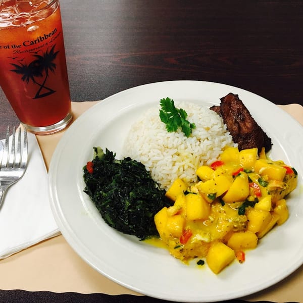 Taste of the Caribbean meal with rice, mango chicken, greens, ribs, and a red drink.